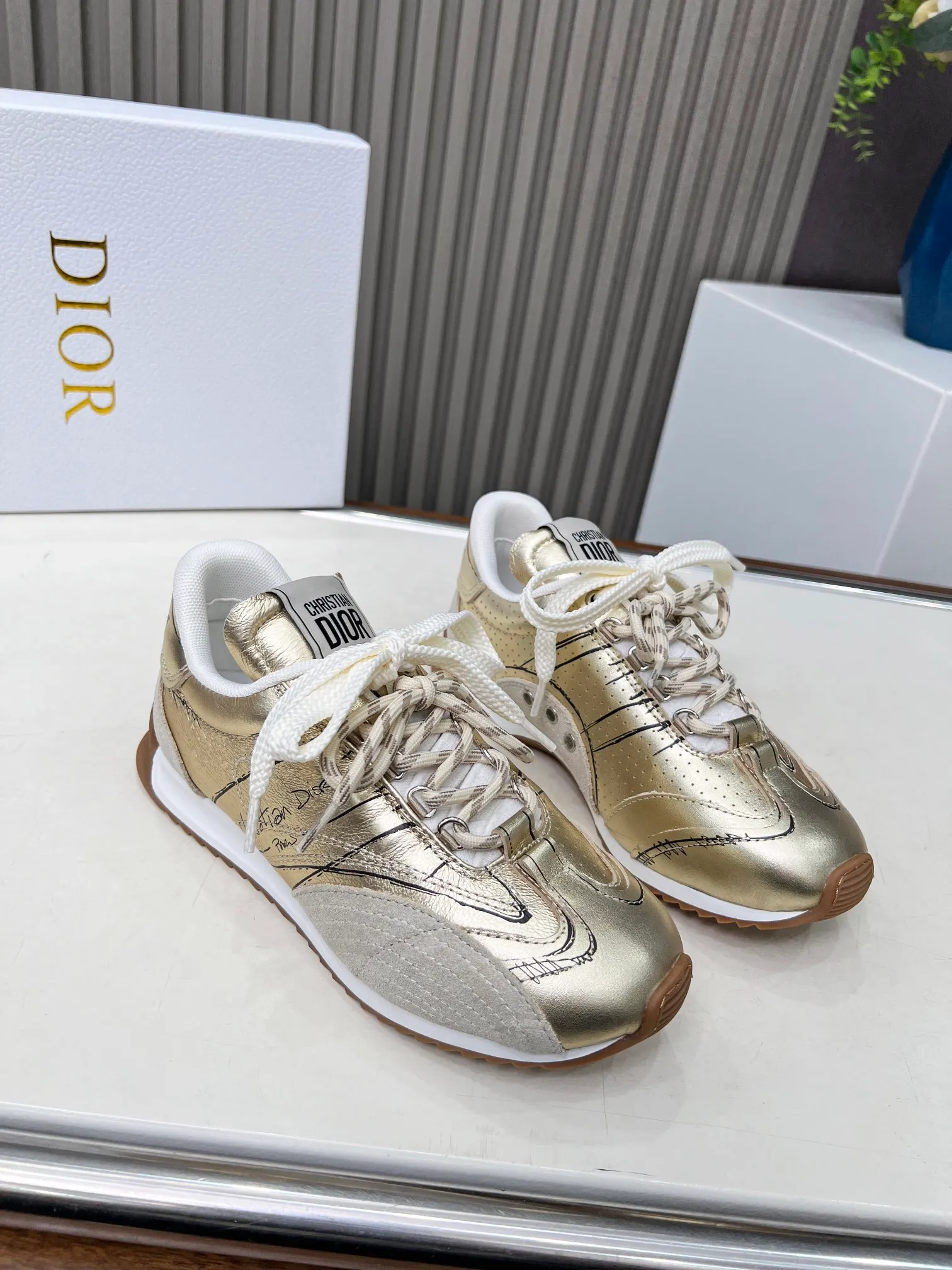 👟👟Ex-factory price 560👟👟 This D-Sketch sneaker is a new product of the 2025 spring and summer ready-to-wear series, highlighting the classic retro aesthetics. Crafted from gold-tone crinkled sheepskin and gold-toned laminated calfskin, it features a printed logo inspired by the shoe's production stages, as well as beige suede calfskin panels and double laces. Hand-written Christian Dior Paris signature on the side, Christian Dior Paris signature panels and plaques on the heel and tongue. Paired with two-tone slim rubber soles, they add a touch of couture to any casual look. Code number: 35~45 Color: black white gold silver